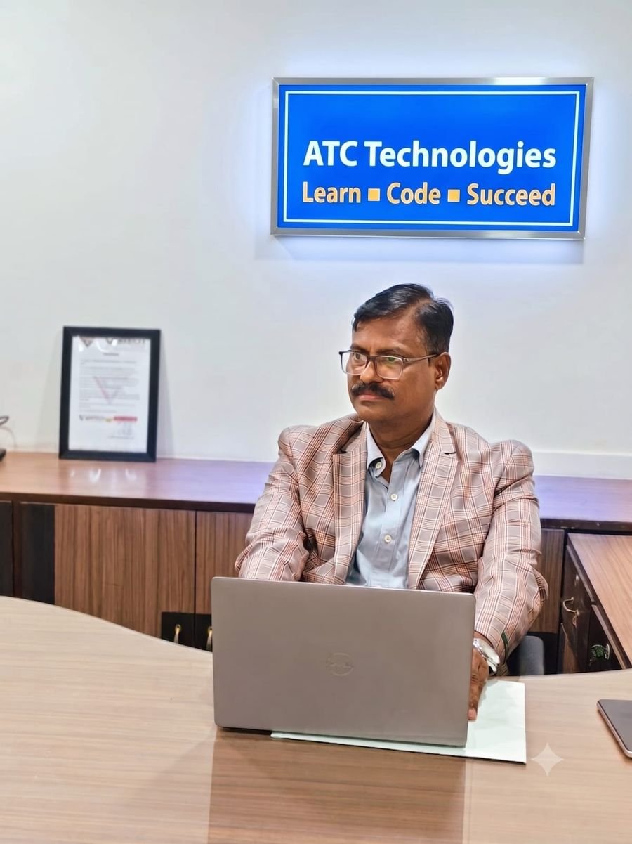Jeyaprakash Naganathapandian, Co-Founder and Director, working at his desk in the ATC Technologies office beneath the Learn, Code, Succeed sign